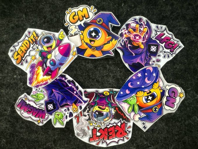 A collection of colorful cartoon-style stickers with various characters, rockets, and text bubbles reading 'GM', 'SEND IT!', 'LFG!', 'WAGMI', 'REKT', and 'GG'.