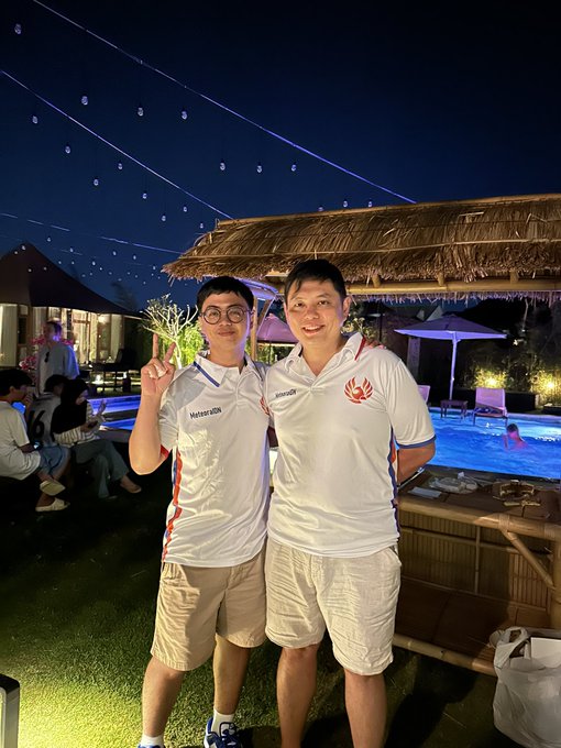 Two young men pose together at night at an outdoor poolside venue with string lights overhead, both wearing white sports jerseys featuring "Meteora" branding and a red logo, representing the South East Asia teams of Meteora_PH and Meteora_IDN.