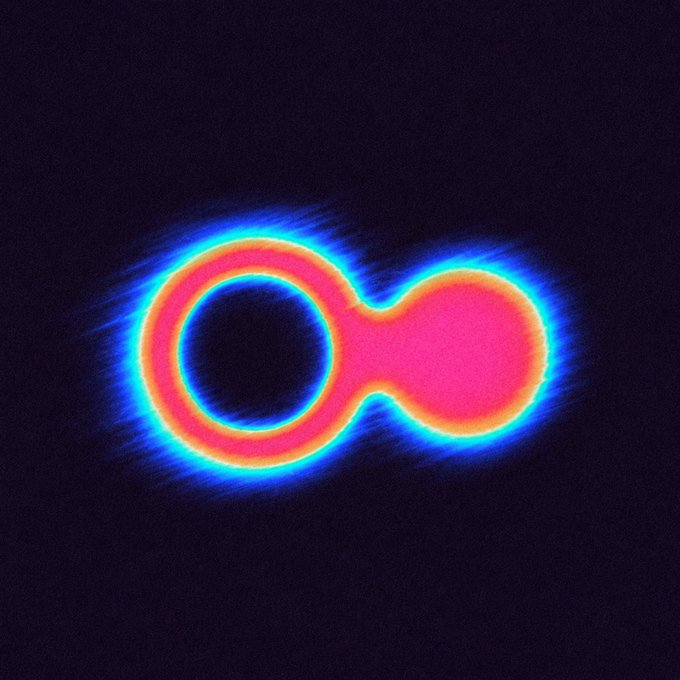 A neon-style glowing infinity symbol in pink, orange, and blue radiates softly against a black background.
