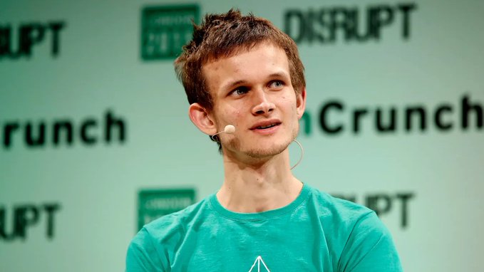 Vitalik Buterin speaking at a TechCrunch Disrupt event, wearing a green t-shirt and headset microphone.