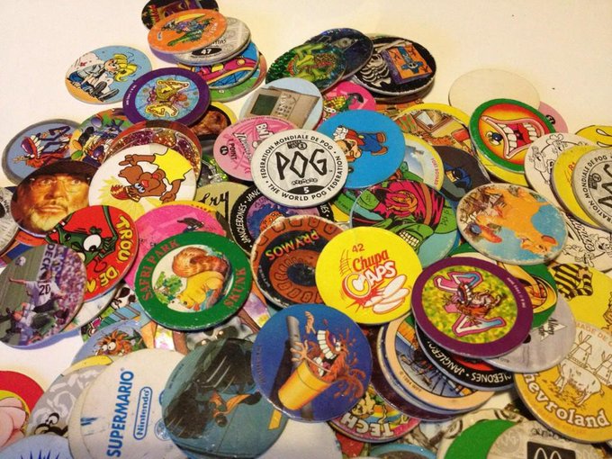 A vibrant pile of colorful Pogs featuring characters and brands like "Chupa Caps," "Super Mario," and "World Pog Federation" evokes 90s nostalgia, fittingly paired with the caption wishing to trade memecoins from that era of childhood collectibles. The worn, scattered discs mirror the speculative, playful nature of crypto trading today.