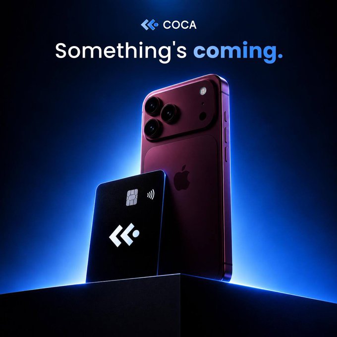 A deep red iPhone stands upright next to a sleek black COCA card featuring the brand's logo and contactless payment symbol, all illuminated against a dramatic blue-lit background. The text "COCA – Something's coming." appears above, teasing a new product launch. The image showcases the COCA Card's integration with everyday tech like smartphones, aligning with the post's emphasis on using crypto for real-world purchases like travel and online shopping.