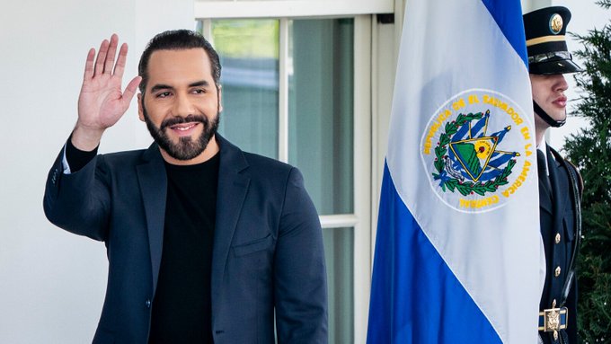 Nayib Bukele, the President of El Salvador, waves next to the nation's flag, as El Salvador continues to accumulate Bitcoin.