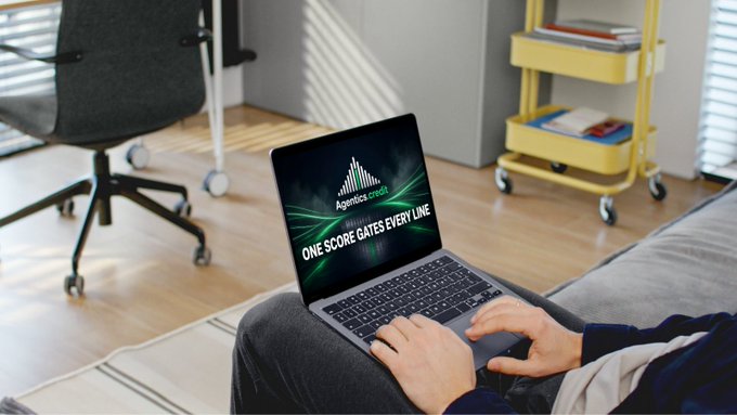 A person using a laptop on their lap in a home setting; the laptop screen displays a logo for 'Agenciatec' with the slogan 'ONE SCORE GATES EVERY LINE'.