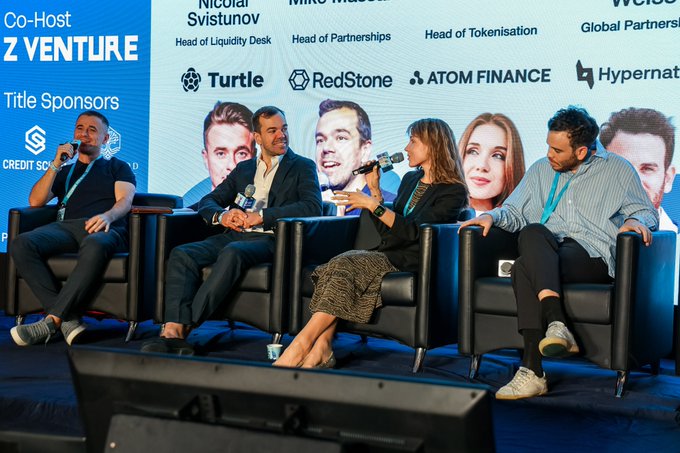 A panel discussion at a conference featuring four seated speakers on stage, with a backdrop displaying names like Nicolai Svisunov, Mike, and Z VENTURE co-host logo.