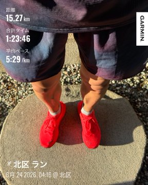 The image features a person standing on a stone platform, wearing red shoes and shorts. The person appears to be taking a picture of themselves with their phone or camera. The photo has been edited to include a time stamp that reads "6:24 PM" in Japanese. This suggests that the photo was taken during the day under natural lighting conditions.