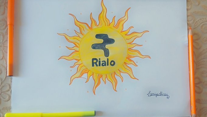 A hand-drawn sun illustration in yellow and orange contains a stylized symbol and the word 'Rialo' written in blue in the center, signed by 'Lamya Alkan' in the corner.