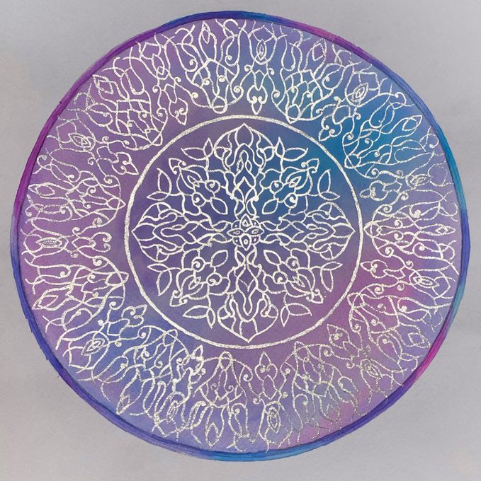 A circular mandala design with intricate white floral and ornamental patterns on an iridescent purple and blue background.