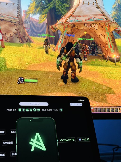 A computer monitor displays a World of Warcraft game scene featuring an orc character, with a smartphone in the foreground showing the Hyperliquid logo.