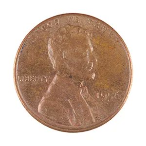 A close-up photograph of a worn, copper-colored US penny coin showing Lincoln's profile and the words 'IN GOD WE TRUST' and 'LIBERTY'.