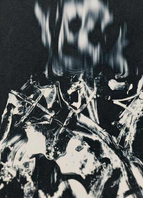 An abstract, high-contrast black and white image that appears to show a distorted face or skull melting into metallic or crystalline textures.