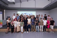 A group photo of around 30 people posing together in what appears to be a modern classroom or lecture hall setting.