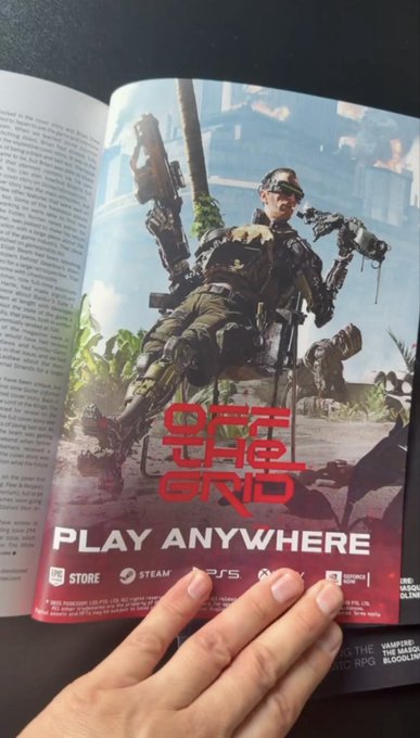 A hand holds open a magazine page featuring an advertisement for the video game 'OFF THE GRID,' showing a soldier character with futuristic gear and the tagline 'PLAY ANYWHERE.'