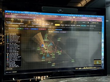A computer monitor displaying a tactical or strategy video game interface with various icons, units, and a map visible on screen.