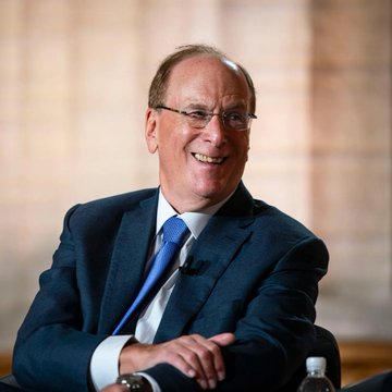 BlackRock CEO Larry Fink smiles, representing the institutional investor continuing to acquire Bitcoin as highlighted in the accompanying post about their $136.5 million purchase.
