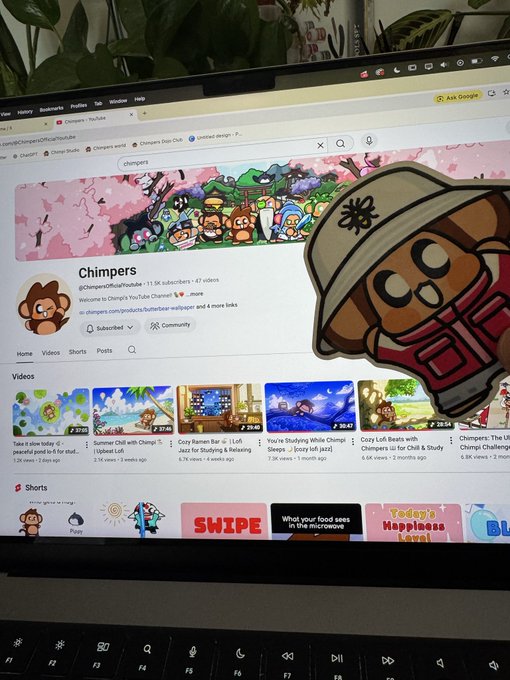 A photograph of a laptop screen displaying the YouTube channel page for 'Chimpers', with a cutout sticker of the Chimpers mascot character overlaid on the right side of the screen.