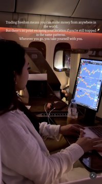 A woman works on a laptop displaying trading charts during a flight, with overlaid text reading "Trading live from means you can make money from anywhere in the world. But there's no point escaping your location if you're still trapped in the same patterns wherever you go, you take yourself with you." The image contrasts with the post's caption by ironically illustrating someone "escaping their location" only to bring their trading habits and patterns with them, reinforcing the message that professional traders don't need to be glued to charts in unconventional settings like 30,000 feet in the air.