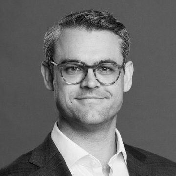 A black-and-white headshot of a man wearing glasses and a suit, smiling slightly, accompanying an article about Bitwise CEO Hunter Horsley discussing Dogecoin's distinctive appeal and growing on-chain activity.