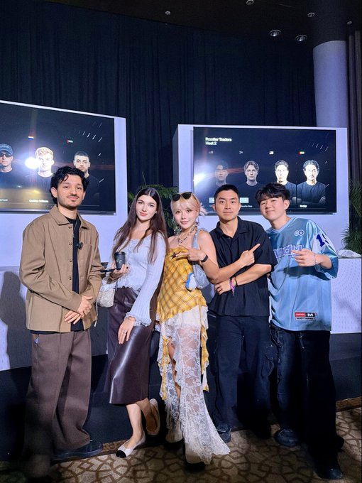 Five people posing together for a photo at an event with screens displaying digital faces behind them, possibly related to a 'Festival of Trophies' showcase.