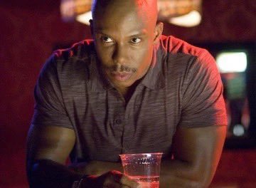 A man holds a plastic cup of beer in a dimly lit bar while looking suspiciously off-camera, as if caught slipping the bill for the round onto a friend's tab. His sly side-eye fits the post's playful callout of someone dodging their share of the bar tab.