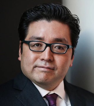 The image features a man wearing glasses, a suit, and a tie. He appears to be dressed professionally for work or business. The caption associated with this image reads "JUST IN: Tom Lee'S Bitmine is currently facing a $10 billion loss on its Ethereum investment." This implies that the man's company might have lost significant amounts of money on their investments in cryptocurrency, specifically on Bitmine. This can lead to negative consequences for the business and those involved, such as potential layoffs or financial instability within the organization.