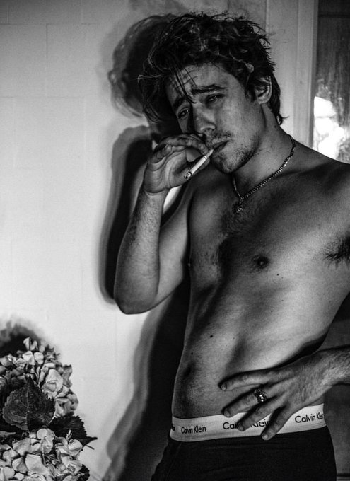 iced tea with a flower on the rim, black and white photo of a shirtless man holding a cigarette against a white wall.