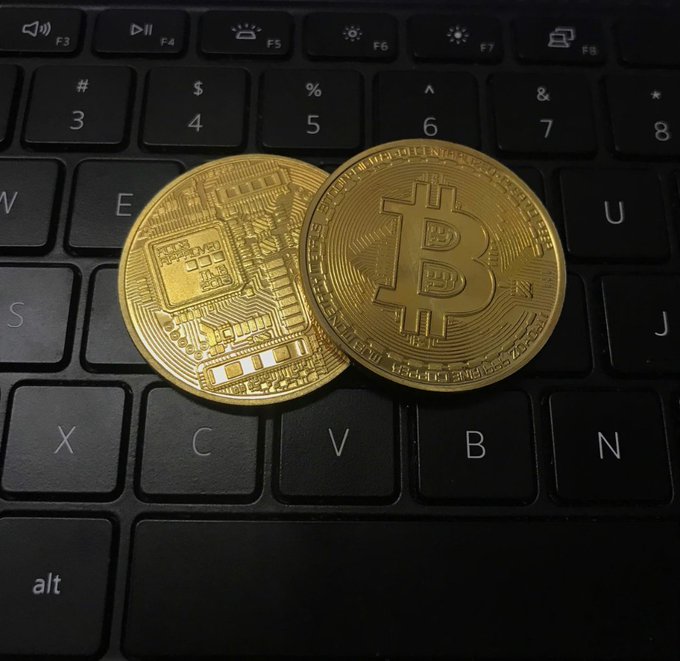 Two physical Bitcoin commemorative coins resting on a black laptop keyboard.