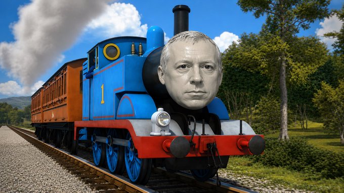 A digitally edited image of Thomas the Tank Engine with the face of a man, traveling along tracks through a green countryside.