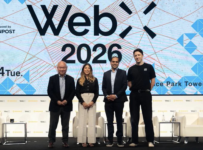 Four individuals stand on stage in front of a large screen displaying "WebX 2026" branding with sponsor logos for Binance and 4Cast visible along the bottom, appearing to be speakers or panelists at the conference event referenced in the post.
