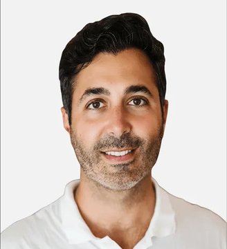 A headshot portrait of a smiling man with dark hair, brown eyes, and stubble, wearing a white polo shirt against a white background.