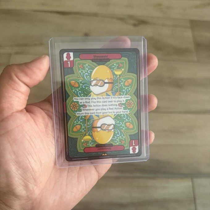 A hand holding a 'Sheeesh!' action card (numbered 1) in a protective plastic sleeve, featuring an olive character and game text explaining it can be played face-down as a Rod.