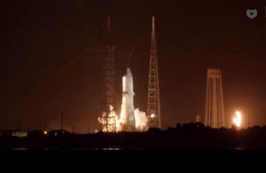 The image shows a rocket launch taking place under the night sky, with a satellite being sent into space by the rocket. The rocket has just exploded, causing smoke to billow out from its top. In the background, there are two towers visible, one of which is likely part of the rocket's structure and another possibly serving as a communication tower for the launch.

The image also contains text that reads "Focus on what is in the image and how it relates to the post". This suggests that the content of the image might be related to a discussion or analysis about the rocket launch, its significance, or the challenges faced during such events.