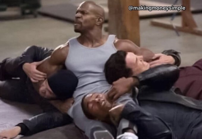 A bald, muscular man in a white tank top is on the ground, holding two other men in a submissive position, with the watermark "@makingmoneysimple" in the upper right corner.