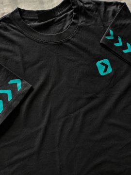 A close-up product photograph of a black athletic t-shirt featuring teal chevron patterns on the sleeves and a teal logo on the chest.