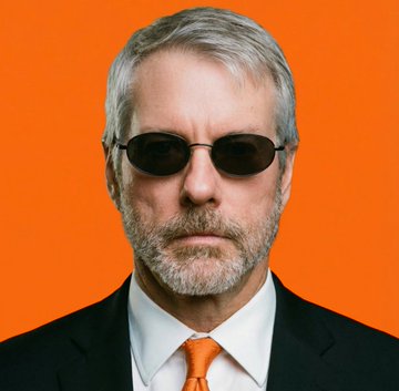 Michael Saylor, the Bitcoin advocate and MicroStrategy executive, is shown wearing his signature dark sunglasses and an orange tie—matching Bitcoin's brand color—against a vibrant orange background, visually reinforcing his bullish stance on cryptocurrency amid his latest comments that governments cannot stop Bitcoin's adoption.
