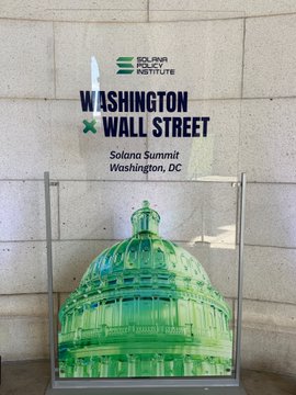 A promotional sign for the "Solana Policy Institute" event titled "Washington × Wall Street" at the Solana Summit in Washington, DC, displayed alongside an image of the U.S. Capitol dome, tying into the post's announcement of digital asset policy discussions ahead of the Senate's "Clarity" vote.