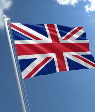 The image shows the United Kingdom flag waving against a blue sky, which connects to the caption as the news is sourced from The Telegraph, a major British newspaper, reporting on Bitcoin's growing status as a "must-have" asset amid shifting investment trends.