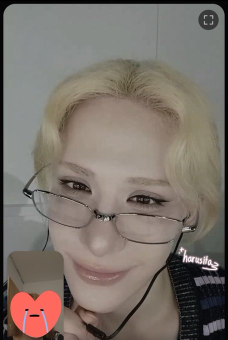 A close-up selfie shows a person with short blonde hair and wire-rimmed glasses smiling softly, with a small inset video in the corner and the text 'harusila' visible on the right.