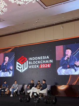 A panel discussion takes place on stage at Indonesia's Blockchain Week 2026, with speakers seated in front of a large screen displaying the event logo and a close-up of one panelist, matching the "Liquidity Hubs: Indonesia as a Regional Hub" session featuring James Eugene, Vice President of Business Development at INDODAX, on Day 2 of @IDBWOfficial.