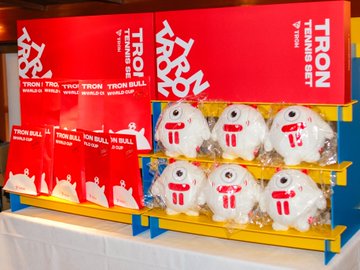 A display table at the TRON Global Friends JAPAN 3rd OFFevent features plush "Tron Bull" mascots and boxes labeled "TRX" (Tronix) arranged for attendees. The setup reflects the post's gratitude to participants, with the branded merchandise likely given out as souvenirs to commemorate the gathering.