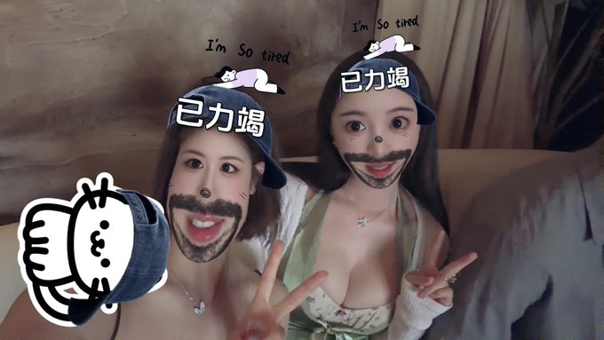 Two women pose together with playful AR filters adding cartoon hats reading 'I'm So tired' and '已力竭', along with fake mustaches, while a thumbs-up graphic appears on the left.