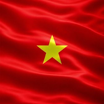 A waving red silk flag with a yellow five-pointed star in the center, representing the flag of Vietnam.