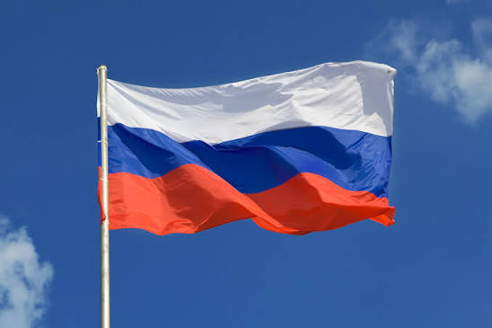 The Russian flag waves against a blue sky, symbolizing the nation as it prepares to enter the cryptocurrency trading market with its Moscow Exchange and SPB Exchange launching new frameworks on September 1.