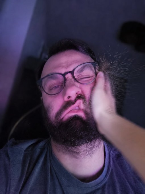 A man with a beard wearing glasses is looking at his face as if something just happened or he's being photobombed. The caption says "day 683 of posting selfie until $ZK hits feeling 24hr price change -10%". This refers to an old post on the website where someone posted their selfie at day 683, and a person added some filter, making it appear that the photo is blurry or photobombed.