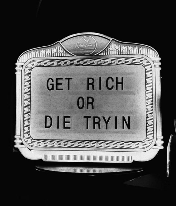 A black-and-white photo of a vintage Splendid movie marquee displaying the phrase "GET RICH OR DIE TRYIN," echoing the post's "Just get rich" sentiment with the famous 50 Cent album/film title.