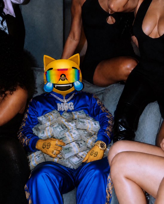 A photo of a person wearing a blue MOG tracksuit and a rainbow cat/fox emoji face mask, holding stacks of cash and wearing jewelry including a watch, rings, and '69' pendants, surrounded by others in black.