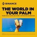 A Binance advertisement displays the headline "THE WORLD IN YOUR PALM" and the text "YOUR GOLD, SILVER AND OTHER COMMODITIES ON BINANCE" above an image of a hand holding gold and silver bars against a blue sky.