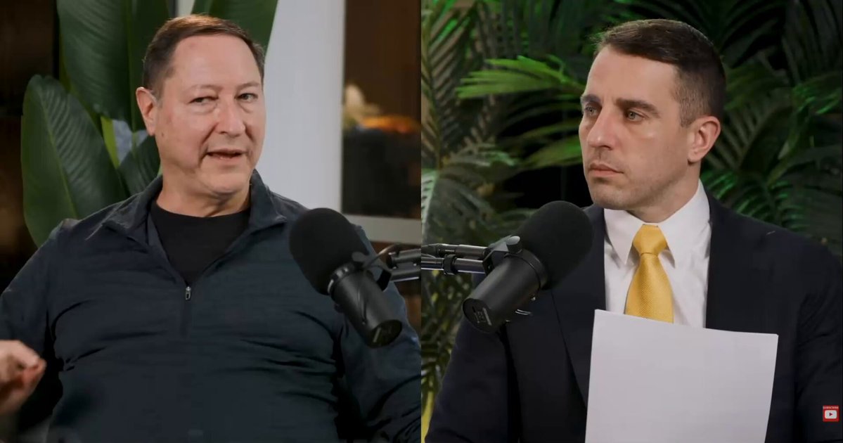 The image shows two men dressed professionally wearing suits and ties, engaged in conversation with microphones positioned above them. One man appears to be explaining or presenting something, while the other is actively listening. The caption "MACRO ANALYST JORDI VISSER JUST LAID OUT THE MOST COMPELLING BITCOIN BULL CASE IN ONE SENTENCE: If the fiat system is $800T and Bitcoin is $2T, there'S a rotation that'll happen. And that'S why deflation equals delever, delever equals Bitcoin to go higher as part of the". The presence of these two men and their professional attire suggests a serious discussion about financial matters or an expert analysis on cryptocurrencies.