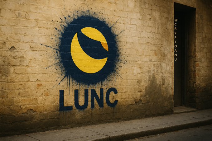 Street art of the yellow LUNC (Terra Luna Classic) logo spray-painted on a brick wall with the text 'LUNC' below it and the watermark '@CRYPTOANU' on the right side.
