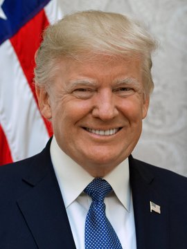 The image features a man wearing a suit, tie, and a pin with an American flag design. The man appears to be smiling for the camera while posing against the backdrop of the American flag. The caption provided after the photo reads "HUGE: President Trump has just ordered the US government to integrate crypto into the banking system." This statement suggests that the man in the suit is likely a political figure, possibly the President or a high-ranking official, who has issued an executive order related to cryptocurrency integration within the financial sector.